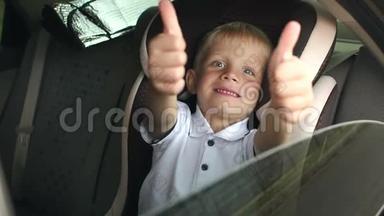 一个快乐的小男孩坐在棕色的儿童汽车座椅上，竖起大拇指。